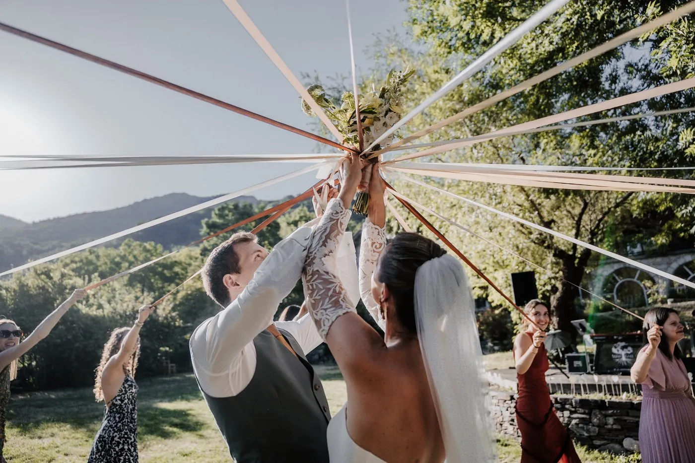 Le jeu des rubans lors d'un cocktail de mariage, les mariés au centre entourés de leurs invités