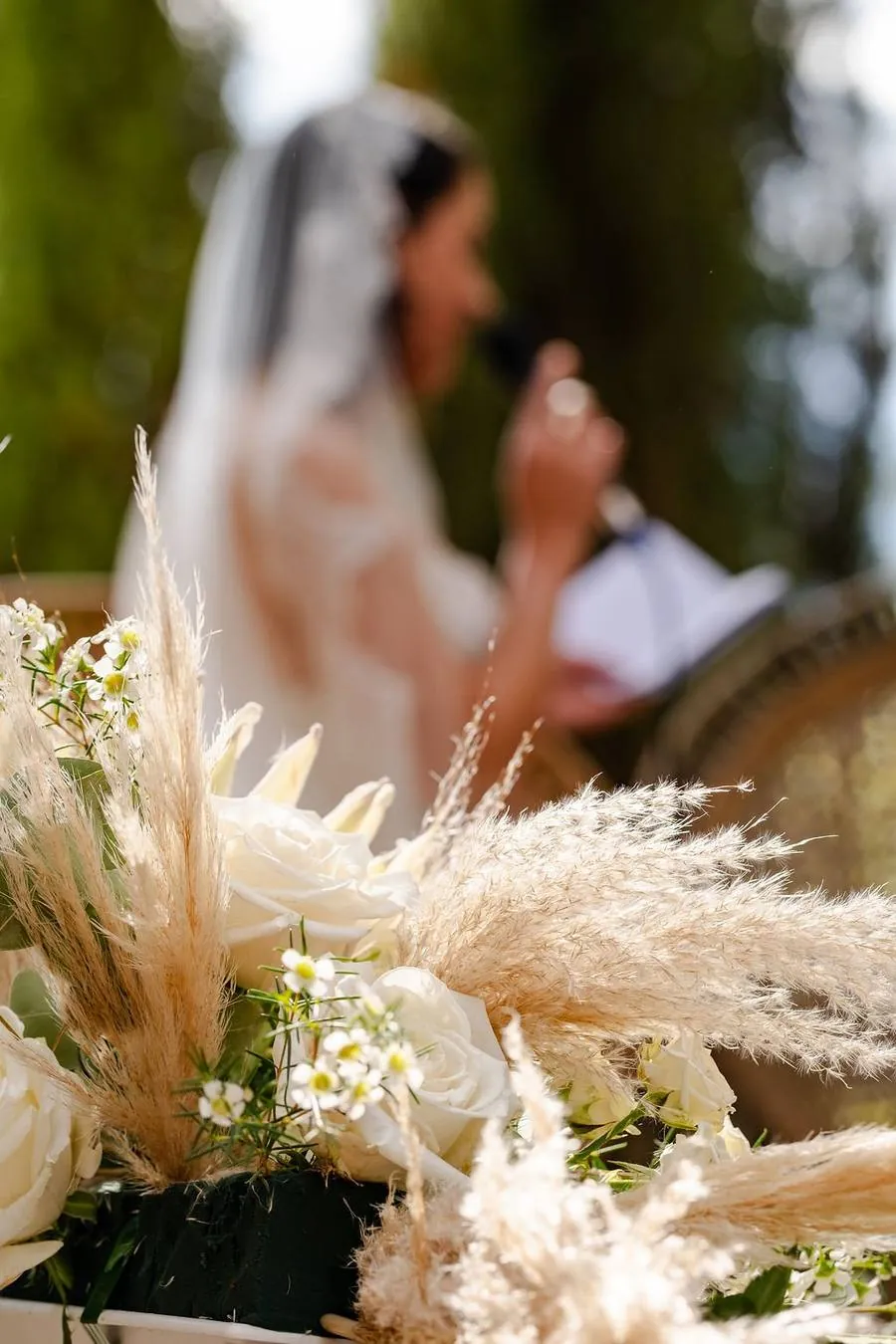 La mariée chante au micro pendant sa cérémonie, bouquet de fleurs blanches au premier plan