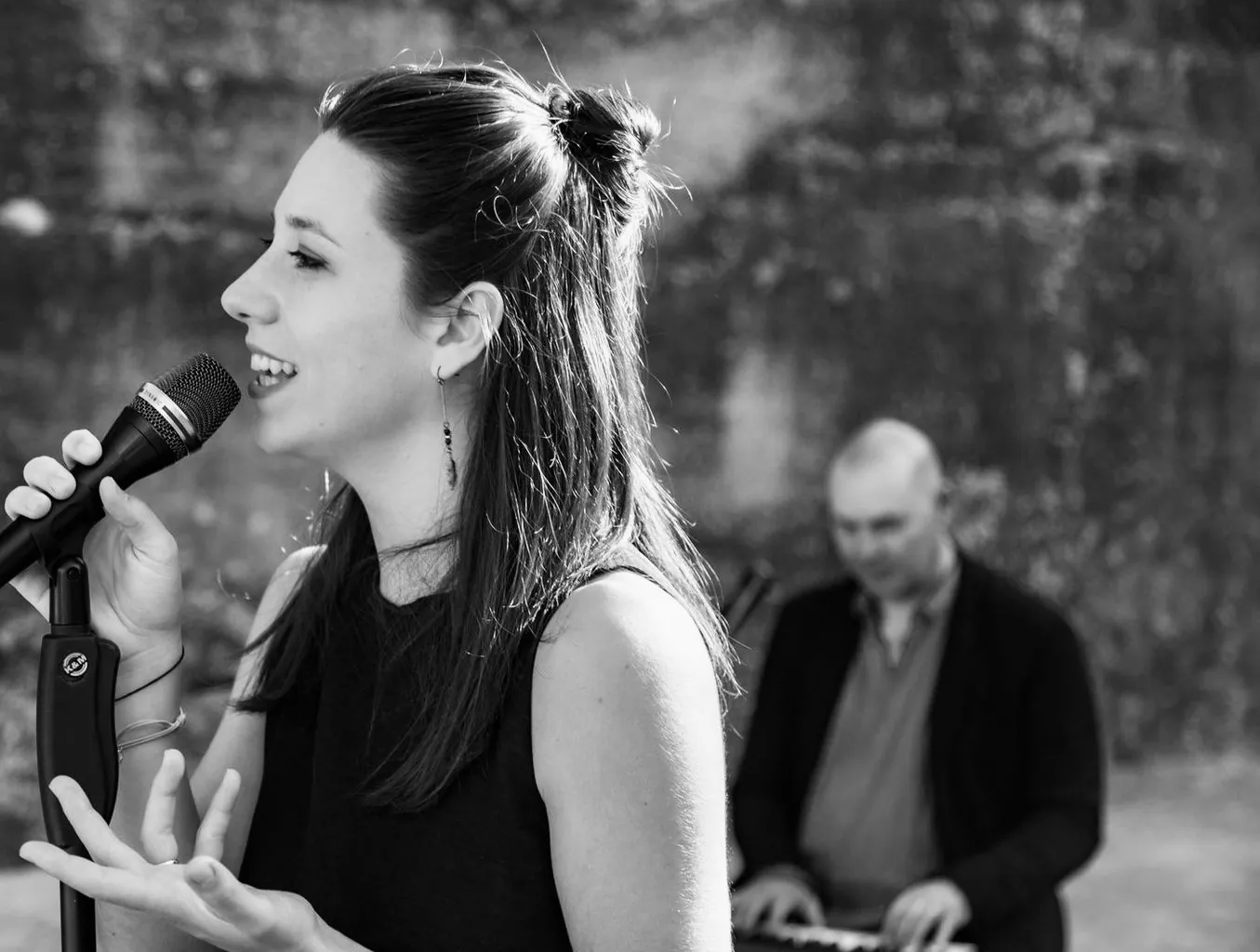 Mathilde chante en souriant lors d'un concert (noir et blanc)